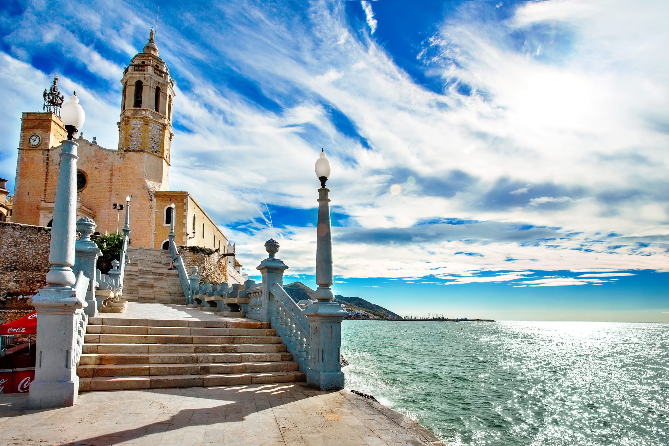 Playa de Sitges con la iglesia de Sant Bartomeu y Santa Tecla al fondo. Hasta llegar a ella, un bello paseo con escaleras.